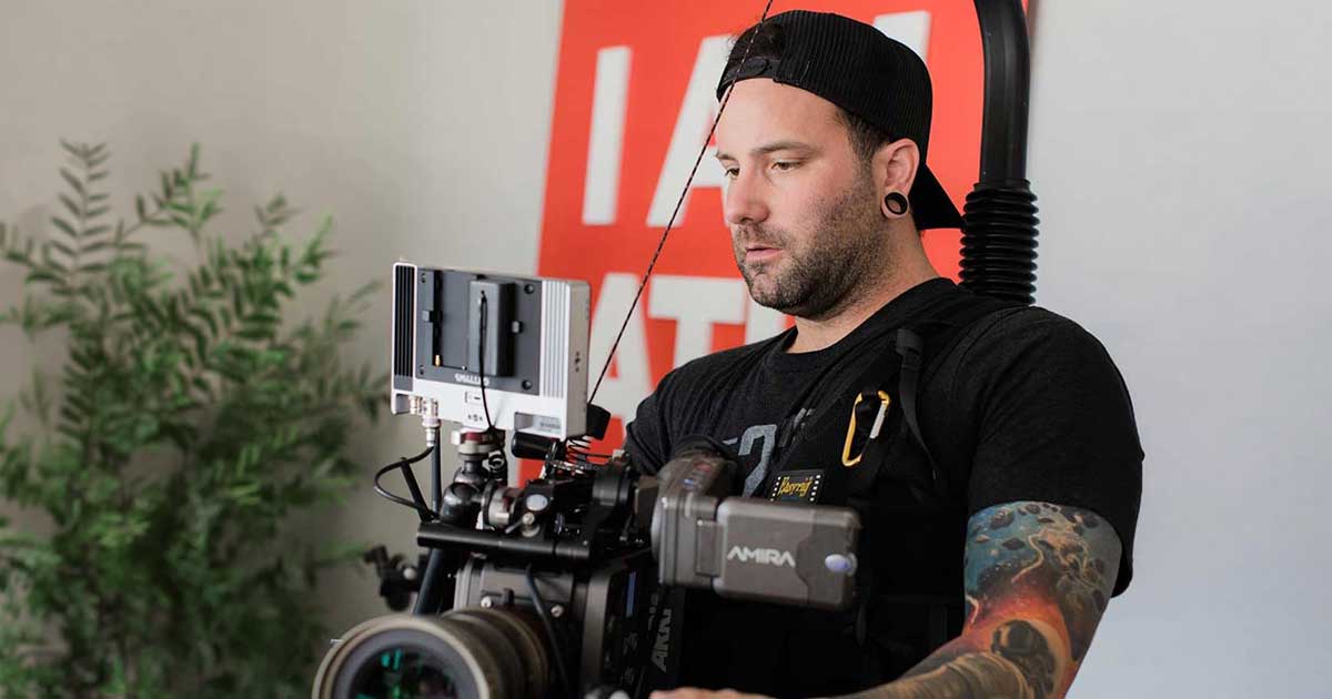 Chris Gray holding a cinema camera on an Easy Rig during a law firm video shoot